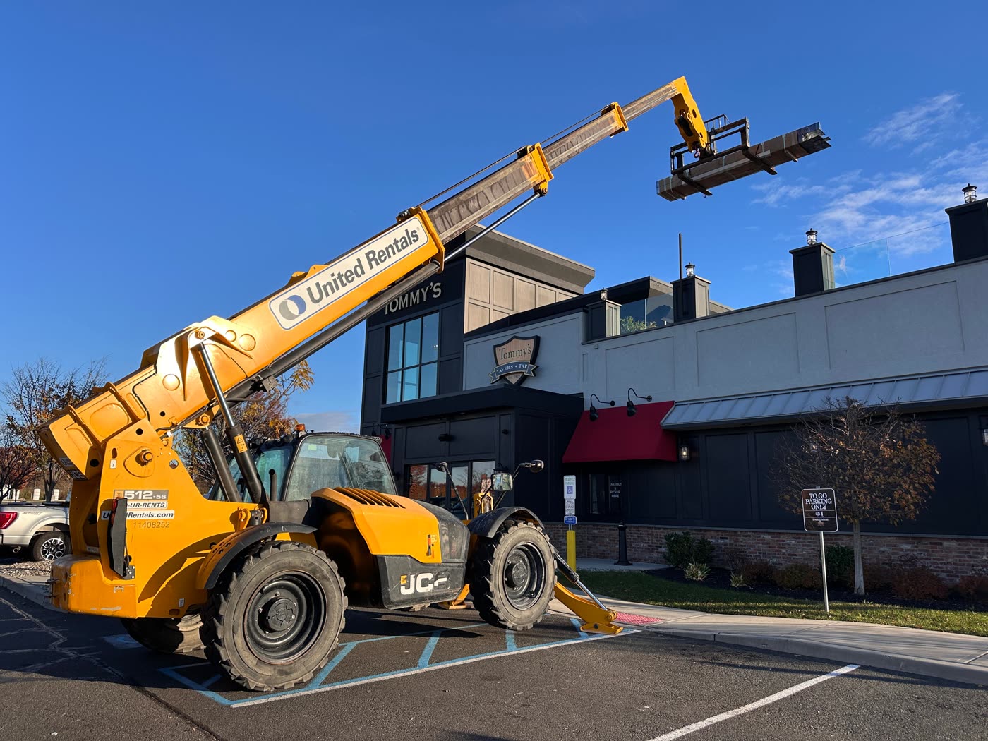 Telehandler lifting pergola materials onto the rooftop of Tommy's Tavern + Tap during a Breslow commercial installation
